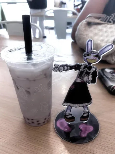an image of the maid jax acrylic standee pointing at the jax lavender tea. photo taken by